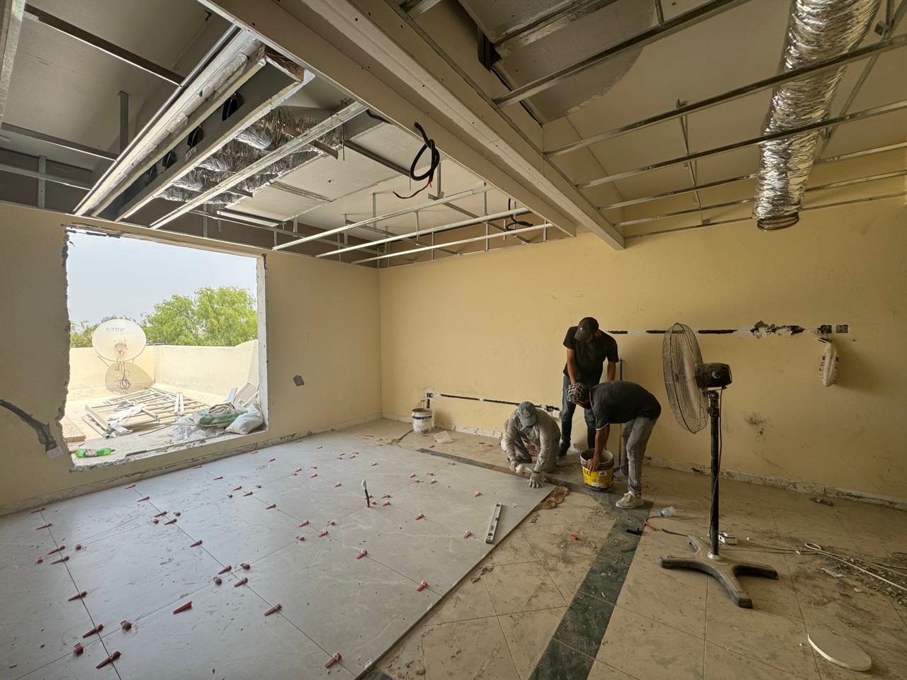 Tiling team working on floor with ceiling framing above
