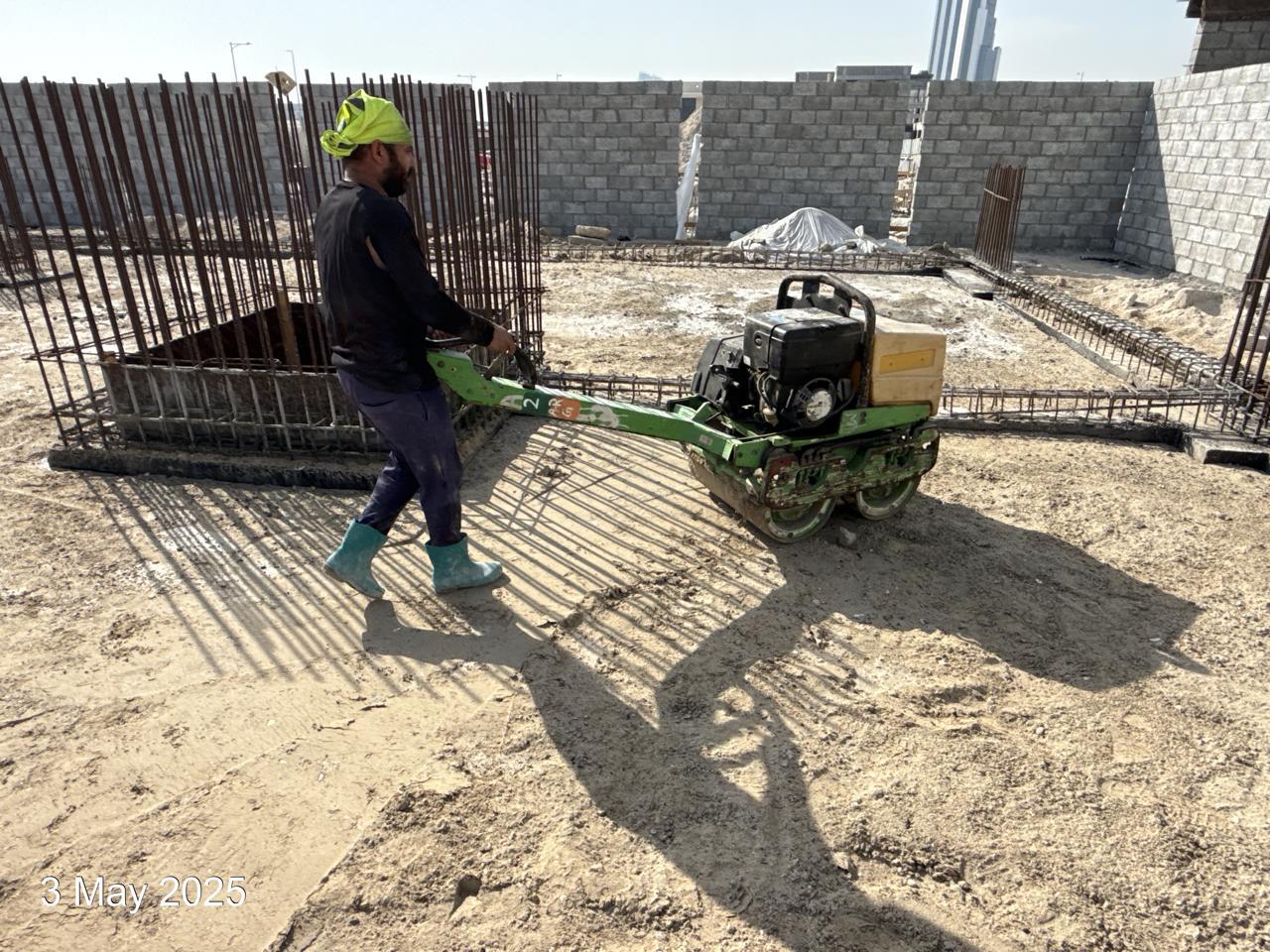 Worker operating plate compactor on site