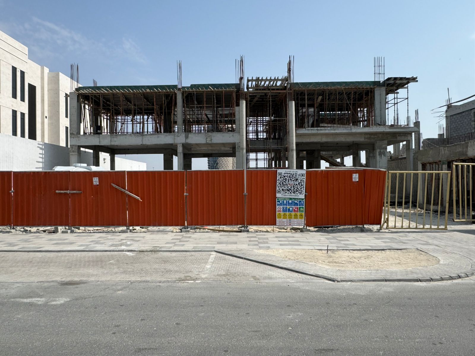 Street view of villa construction behind site hoarding