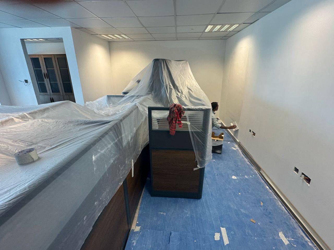 Cubicles covered with plastic sheeting during wall painting