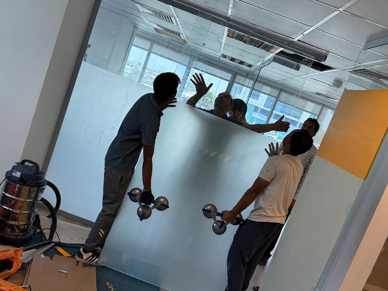 Glass panel installation with suction lifters in office