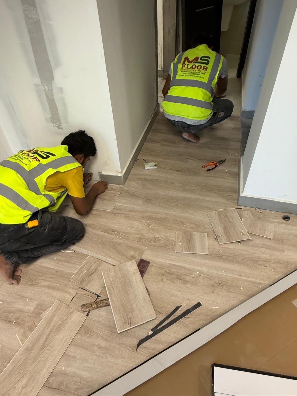 Vinyl flooring installation by workers in corridor