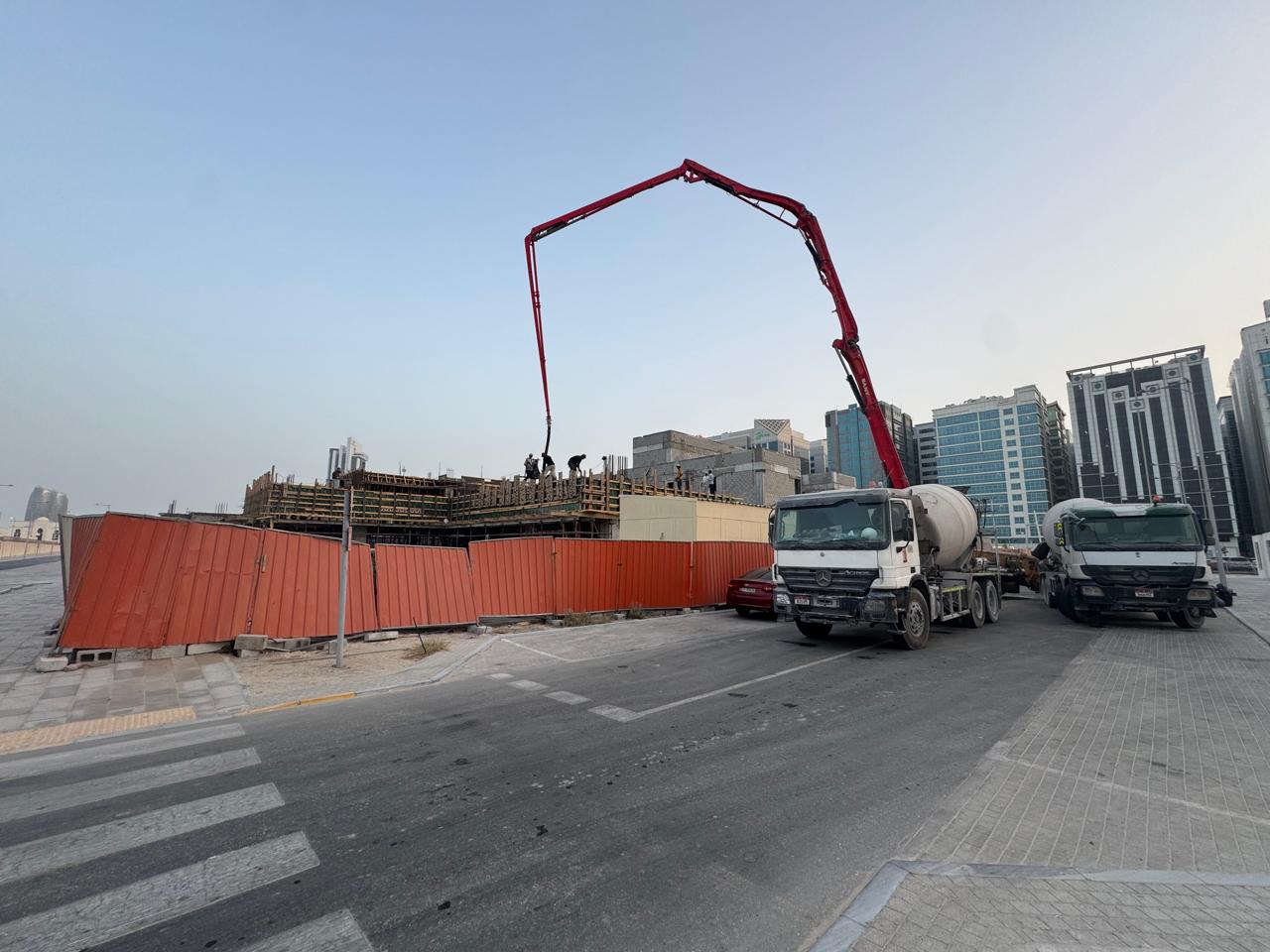 Concrete pump truck pouring slab from street level