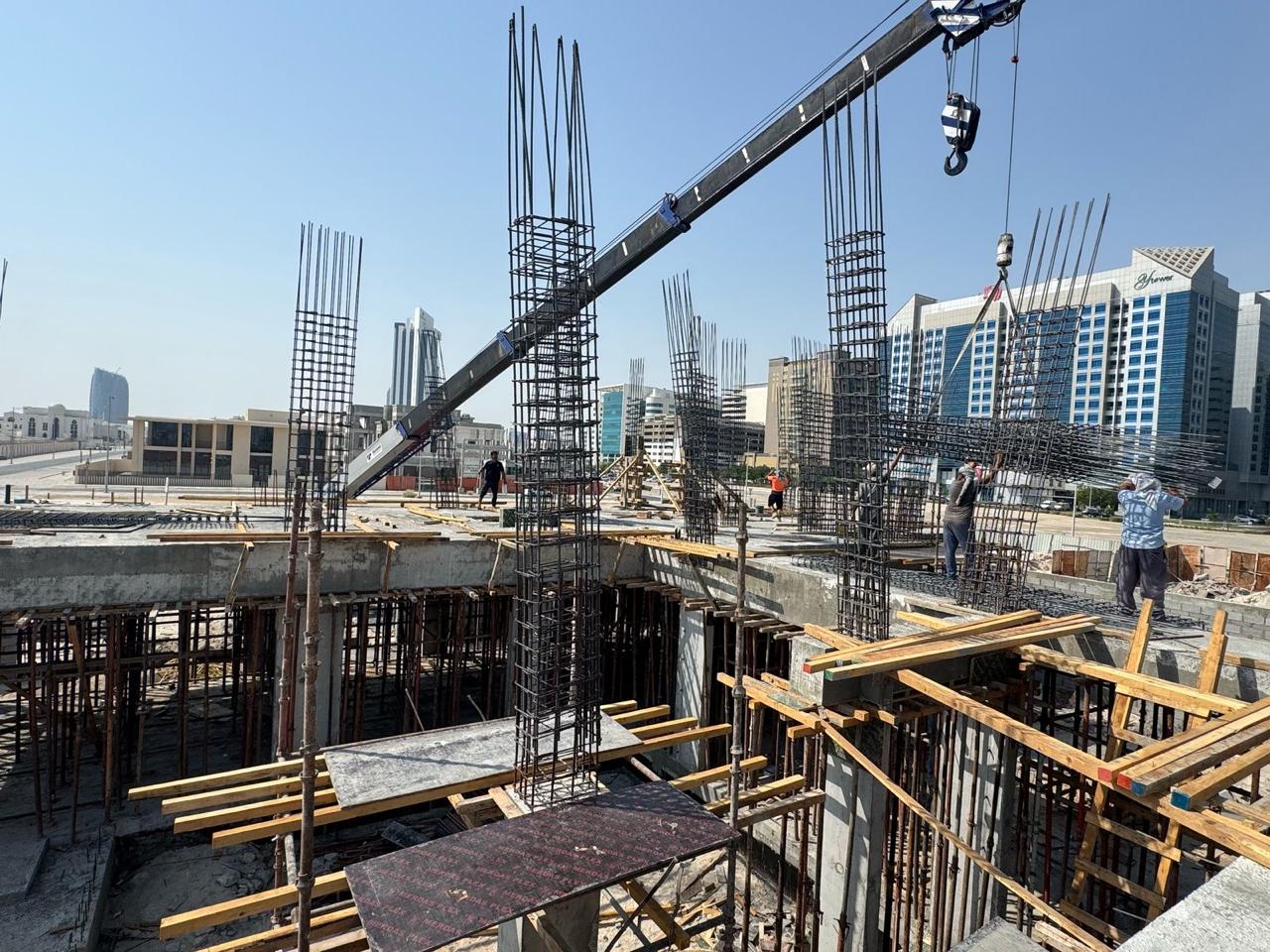 Crane lifting rebar with column reinforcement on commercial site