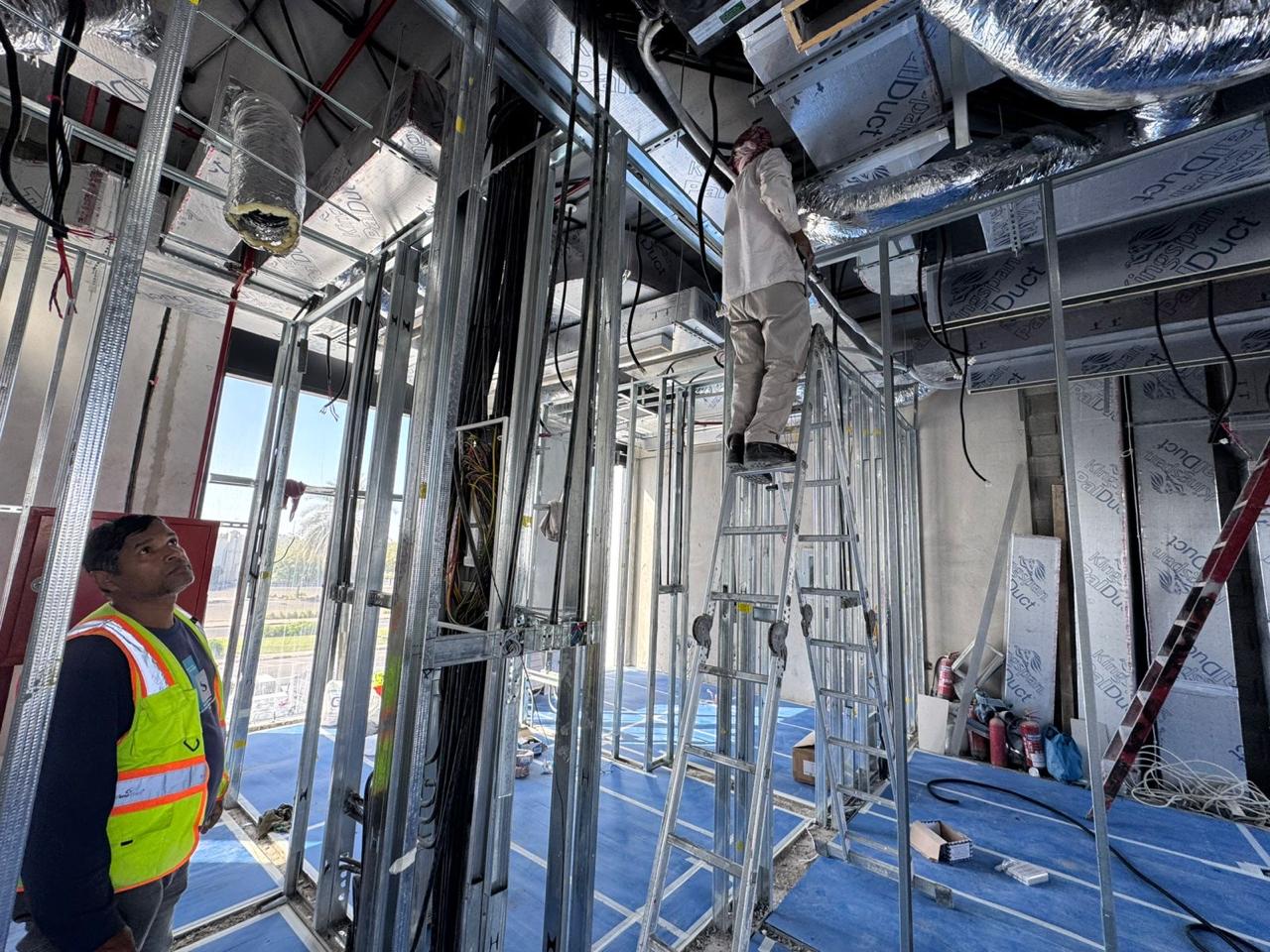 MEP duct framing and cabling with workers on ladder