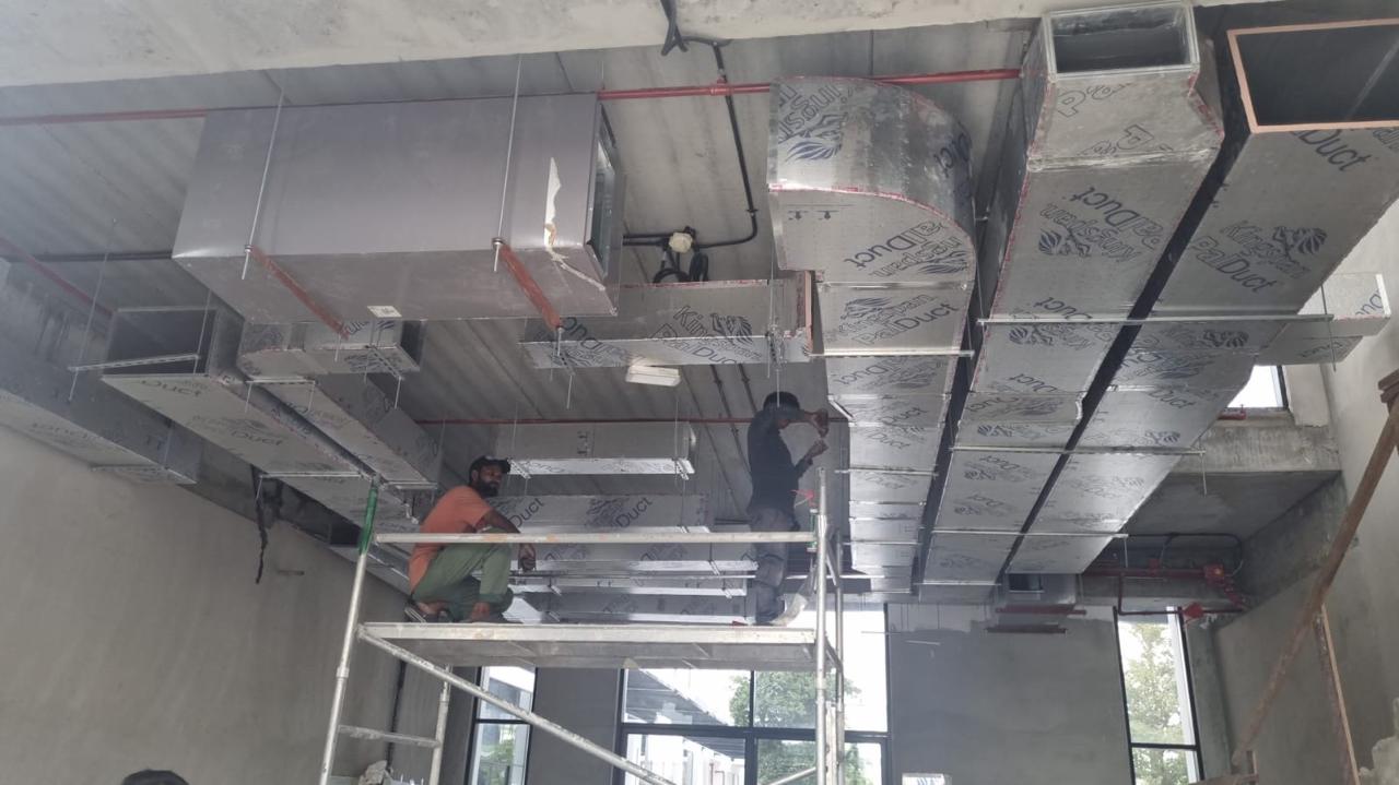 HVAC duct installation on scaffolding in commercial building