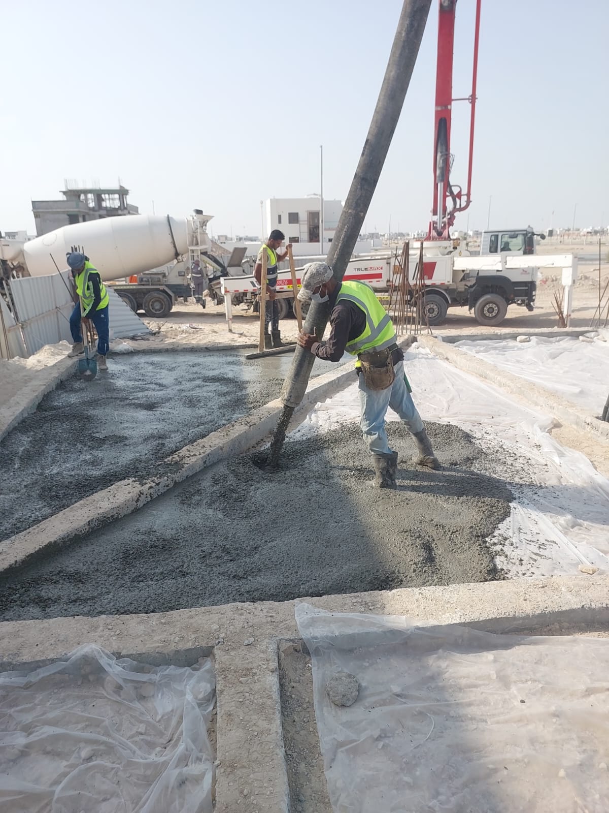 Workers pouring concrete on foundation with mixer truck