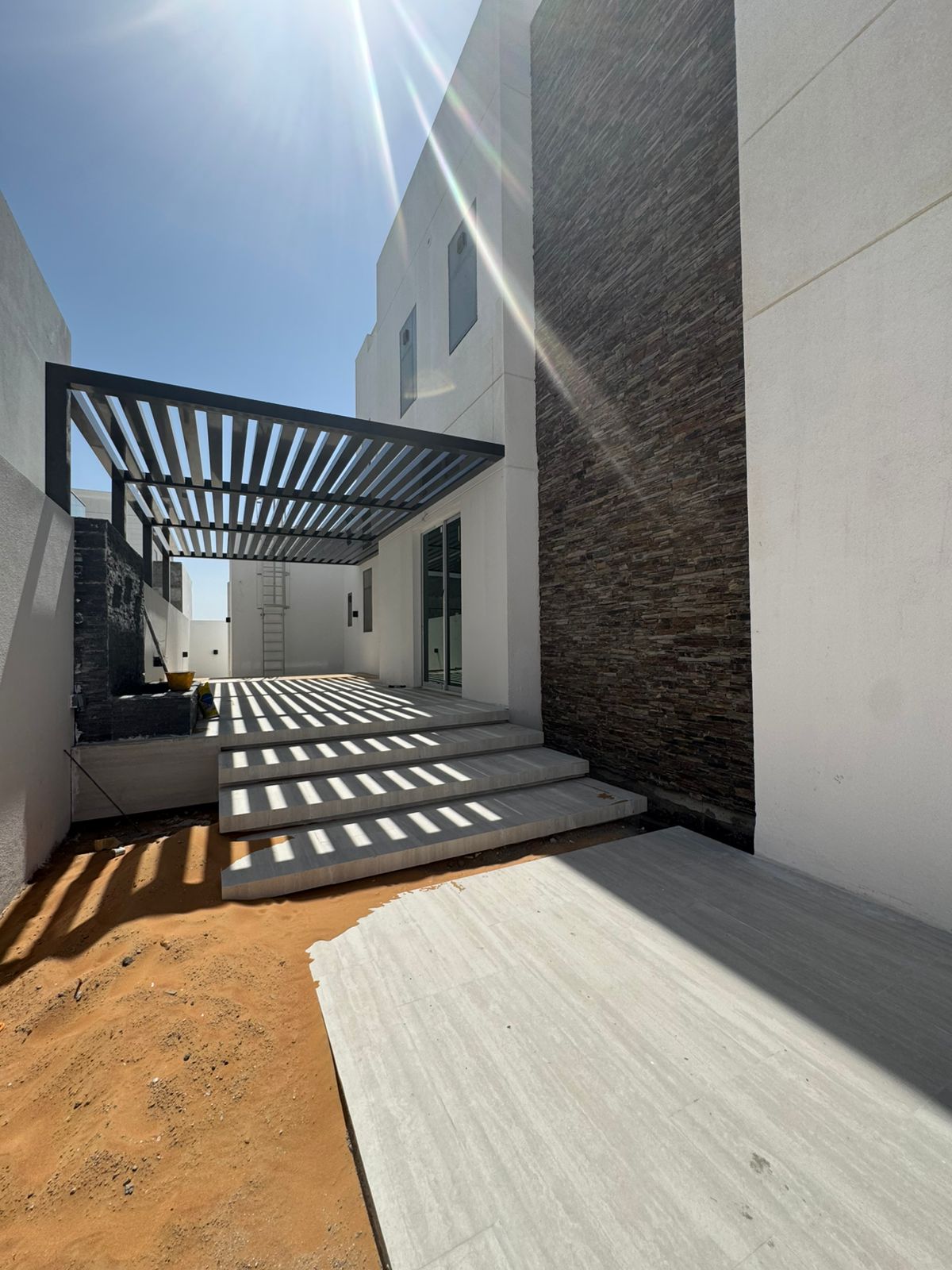 Pergola entrance with stone cladding and sunlight Abu Dhabi