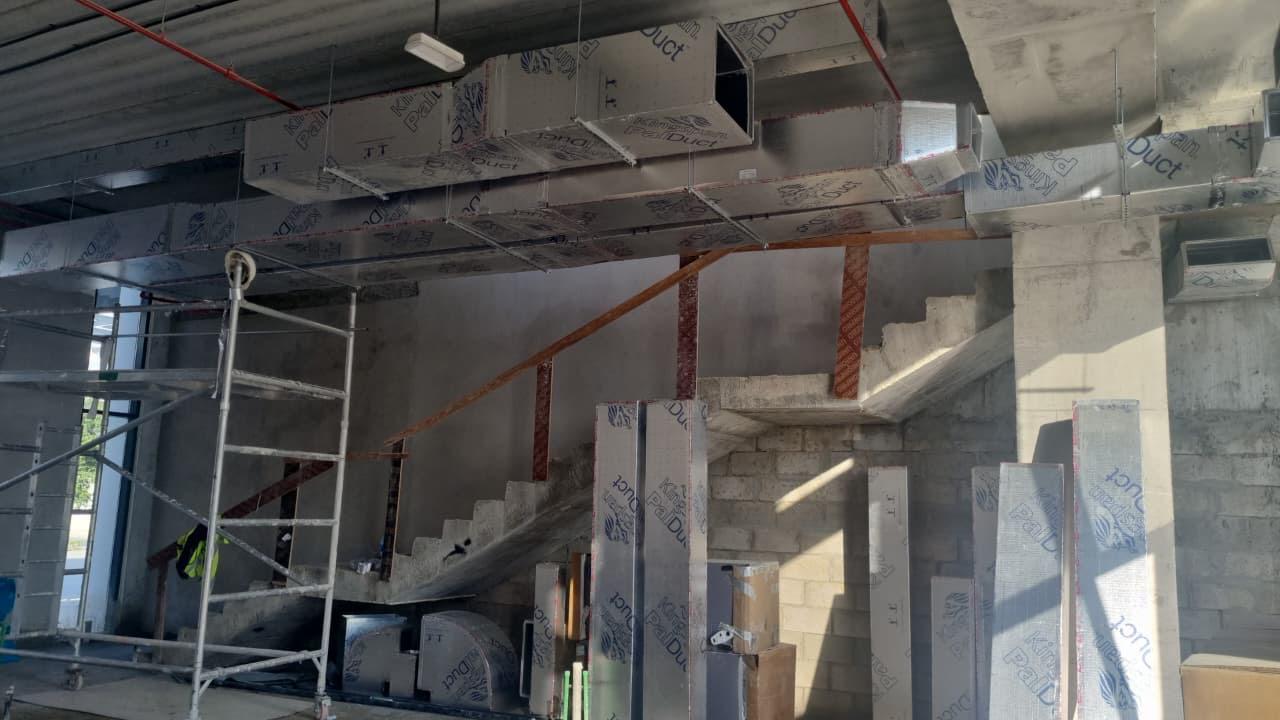 HVAC duct routing near stairwell with scaffolding