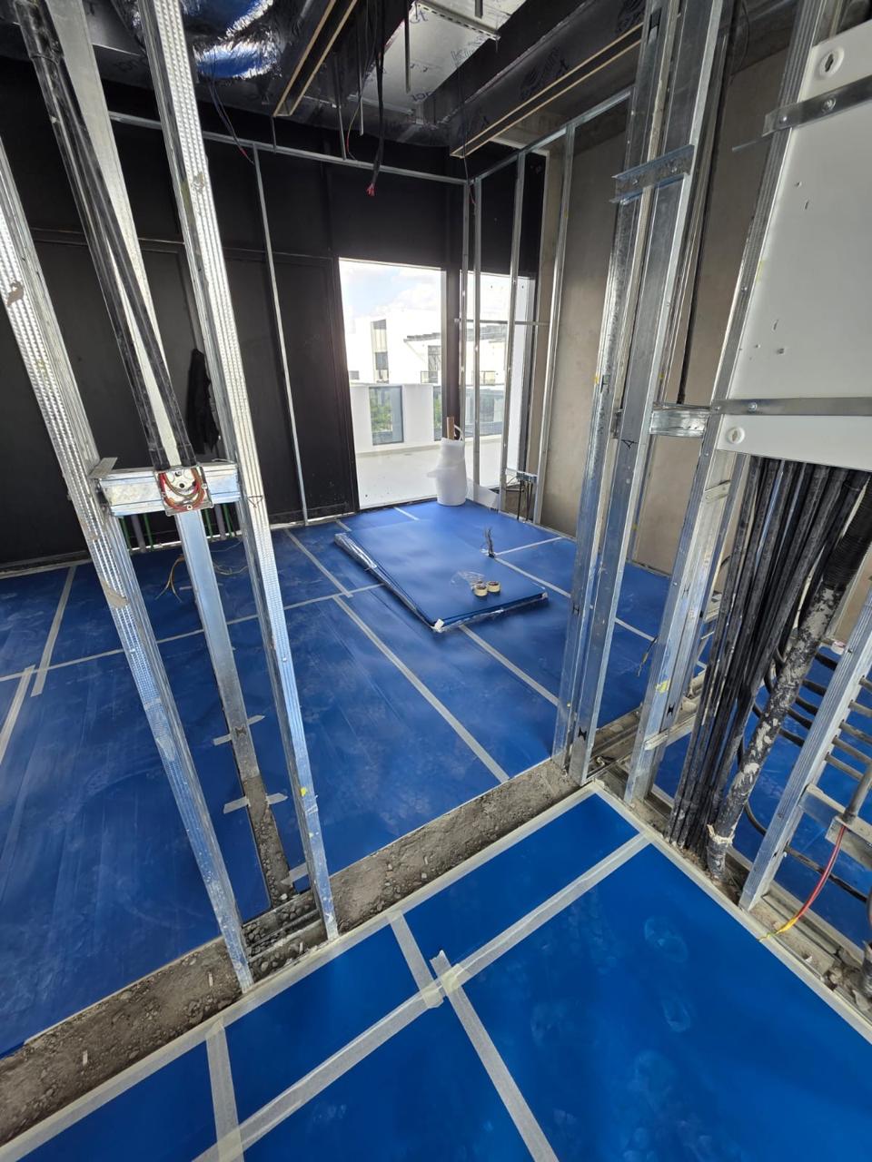 Metal stud framing with blue floor protection sheeting