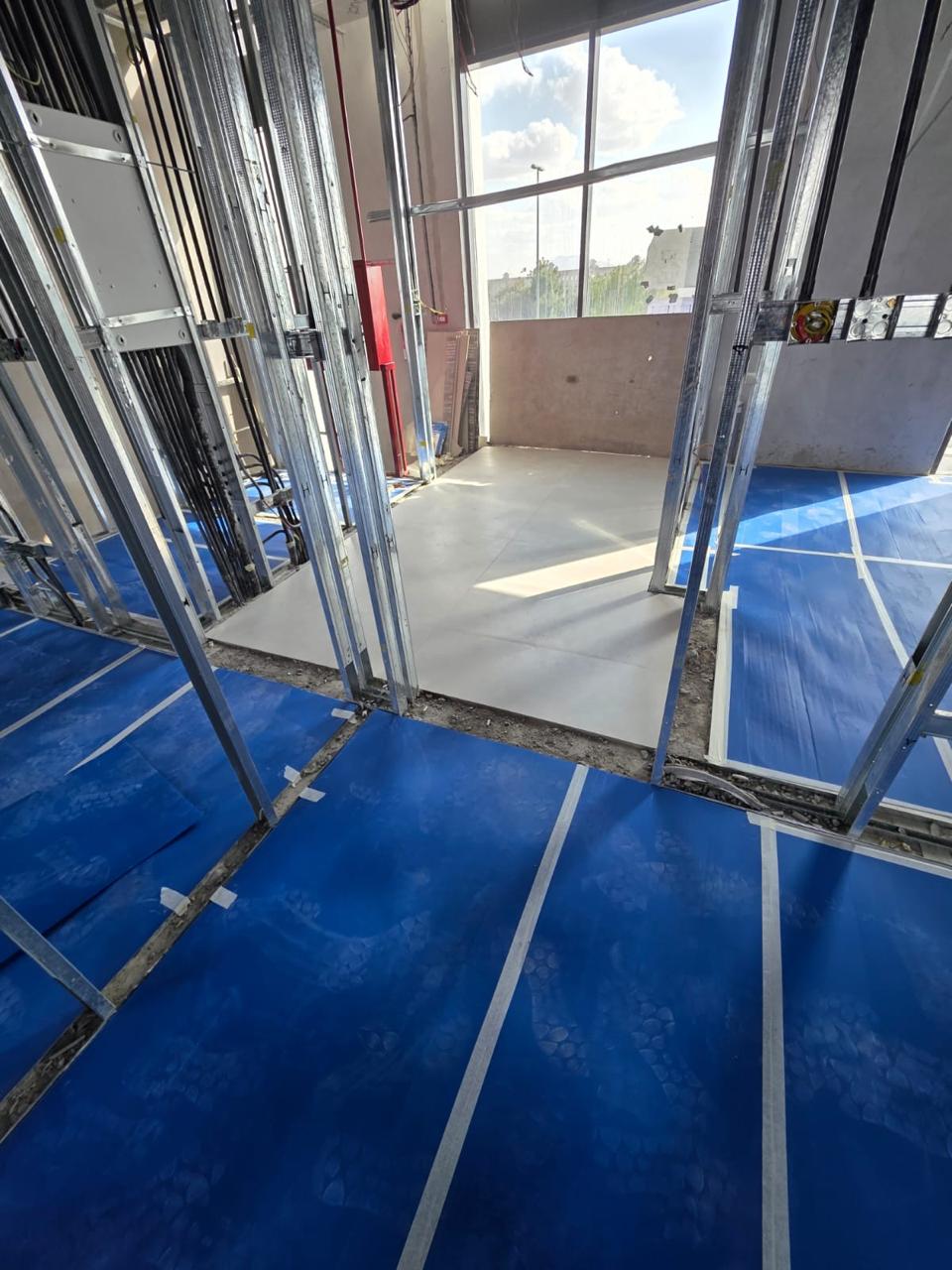 Metal stud partitions with blue waterproofing and glazing view